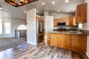 Kitchen with kitchen peninsula, appliances with stainless steel finishes, vaulted ceiling, ceiling fan, and dark hardwood / wood-style floors