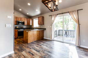 Kitchen with kitchen peninsula, appliances with stainless steel finishes, dark hardwood / wood-style flooring, and sink