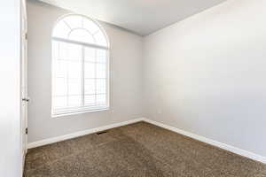 Carpeted empty room with a textured ceiling and a wealth of natural light