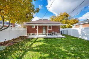 Rear view of house with a lawn and a patio