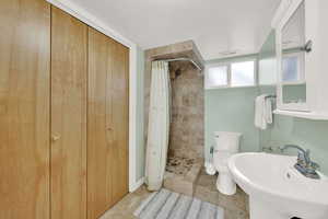 Bathroom featuring tile patterned floors, a textured ceiling, toilet, and walk in shower