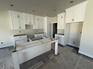 Kitchen with recessed lighting, a kitchen island, white cabinets, and baseboards