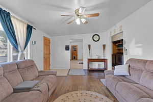 Living room featuring dark hardwood / wood-style flooring, vaulted ceiling, and ceiling fan