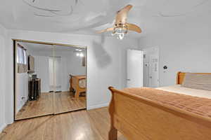 Bedroom with a closet, light hardwood / wood-style flooring, and ceiling fan