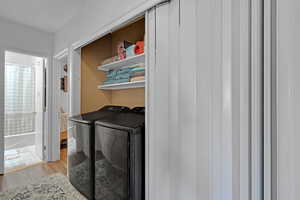 Clothes washing area with light hardwood / wood-style flooring and washer and clothes dryer