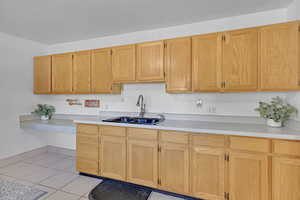 Kitchen with light brown cabinets, light tile patterned floors, and sink