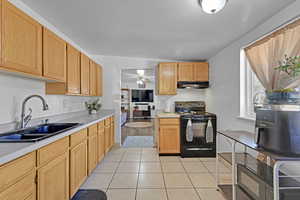 Kitchen featuring lofted ceiling, sink, black electric range, ceiling fan, and light tile patterned flooring