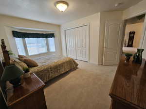 Carpeted bedroom featuring a closet and a textured ceiling