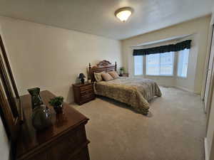 Bedroom featuring light colored carpet and a textured ceiling