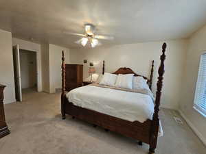 Carpeted bedroom with ceiling fan and a textured ceiling