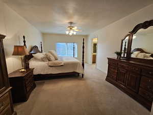 Bedroom with light carpet, ceiling fan, and a textured ceiling