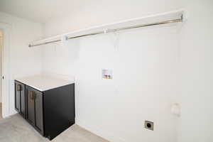 Laundry area with electric dryer hookup, light tile patterned flooring, and hookup for a washing machine