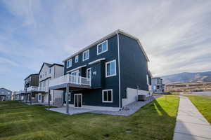 Rear view of property with a mountain view, central AC, a patio area, and a lawn