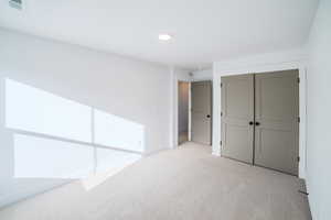 Unfurnished bedroom featuring light colored carpet and a closet