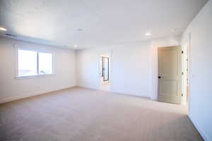 Carpeted spare room featuring a textured ceiling