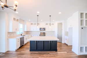 Kitchen featuring white cabinets, pendant lighting, a center island, and stainless steel appliances