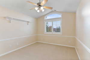 Empty room with carpet, ceiling fan, and lofted ceiling