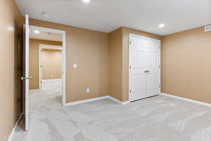 Unfurnished bedroom with light colored carpet and a closet