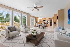 Living room featuring light tile patterned floors, ceiling fan with notable chandelier, and plenty of natural light