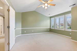 Carpeted spare room with ceiling fan and vaulted ceiling