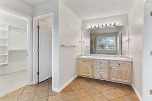 Bathroom featuring tile patterned flooring, vanity, and a textured ceiling