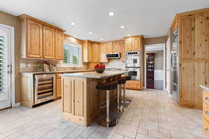 Kitchen featuring stainless steel appliances, wine cooler, tasteful backsplash, and a kitchen island