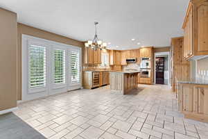 Kitchen featuring decorative backsplash, stainless steel appliances, beverage cooler, a chandelier, and a center island