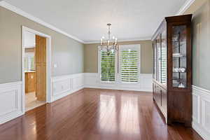 Unfurnished dining area featuring a healthy amount of sunlight, dark wood-type flooring, and an inviting chandelier