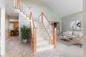 Stairway with carpet flooring and high vaulted ceiling