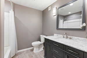 Full bathroom featuring hardwood / wood-style floors, vanity, toilet, and shower / tub combo with curtain