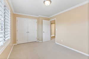 Unfurnished bedroom featuring light carpet, a closet, and crown molding