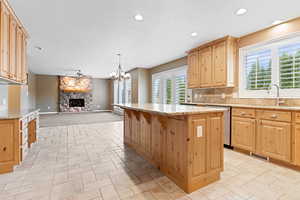 Kitchen featuring a fireplace, a kitchen island, a wealth of natural light, and light stone counters