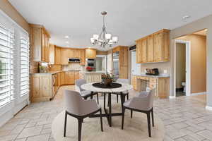 Kitchen with light stone counters, hanging light fixtures, appliances with stainless steel finishes, and a chandelier