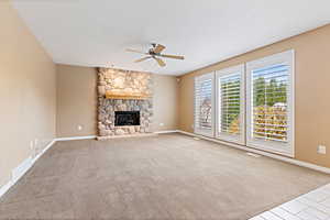 Unfurnished living room with light carpet, a fireplace, and ceiling fan