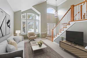 Living room featuring carpet floors, high vaulted ceiling, a notable chandelier, and ornamental molding