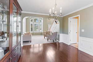 Unfurnished room with an inviting chandelier, ornamental molding, and hardwood / wood-style flooring