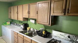 Clothes washing area featuring cabinets, sink, and washing machine and clothes dryer