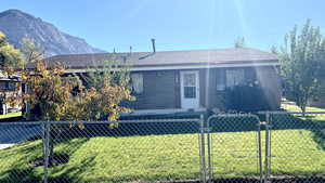 Single story home featuring a mountain view and a front lawn