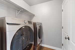 Washroom featuring INCLUDED washer and dryer and dark wood-type flooring