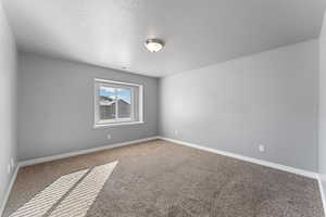 Carpeted spare room featuring a textured ceiling