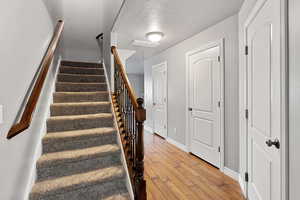 Stairway with hardwood / wood-style floors and a textured ceiling