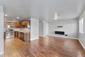 Kitchen with light stone counters, sink, stainless steel appliances, and wood-type flooring