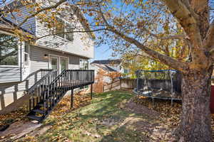 View of yard with a deck and a trampoline