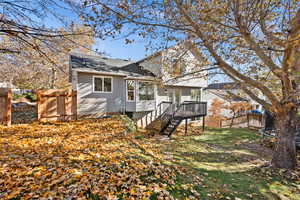 Rear view of house with a deck, a trampoline, and a yard