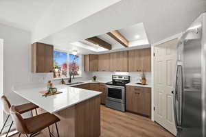 Kitchen featuring kitchen peninsula, appliances with stainless steel finishes, a breakfast bar, sink, and light hardwood / wood-style flooring