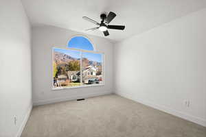 Carpeted empty room with a mountain view, ceiling fan, and lofted ceiling