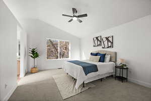 Carpeted bedroom featuring ceiling fan, lofted ceiling, and ensuite bathroom