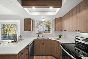 Kitchen featuring a tray ceiling, sink, a textured ceiling, and appliances with stainless steel finishes