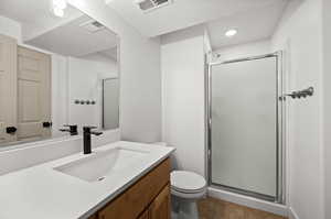 Bathroom with tile patterned flooring, vanity, a shower with shower door, and toilet