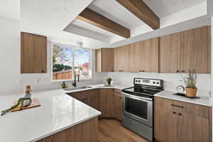 Kitchen with beam ceiling, sink, dark wood-type flooring, kitchen peninsula, and stainless steel electric range